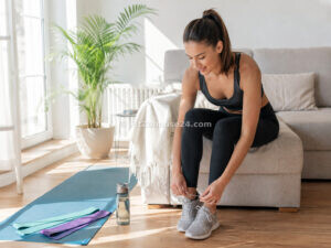 Frau schnürt motiviert ihre Sportschuhe vor dem Heimtraining im Wohnzimmer
